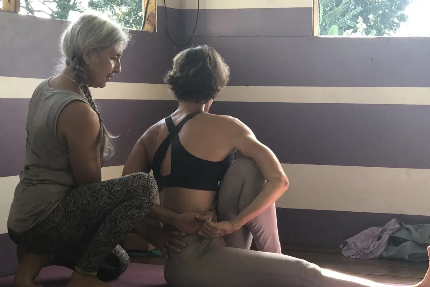 Carole, professeure du studio, accompagne de ses mains la posture assise d'une élève.