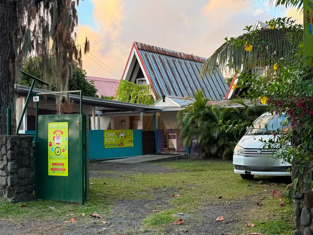 Le jardin après le portail : les bâtiments du centre de loisirs et une allée d'herbe.